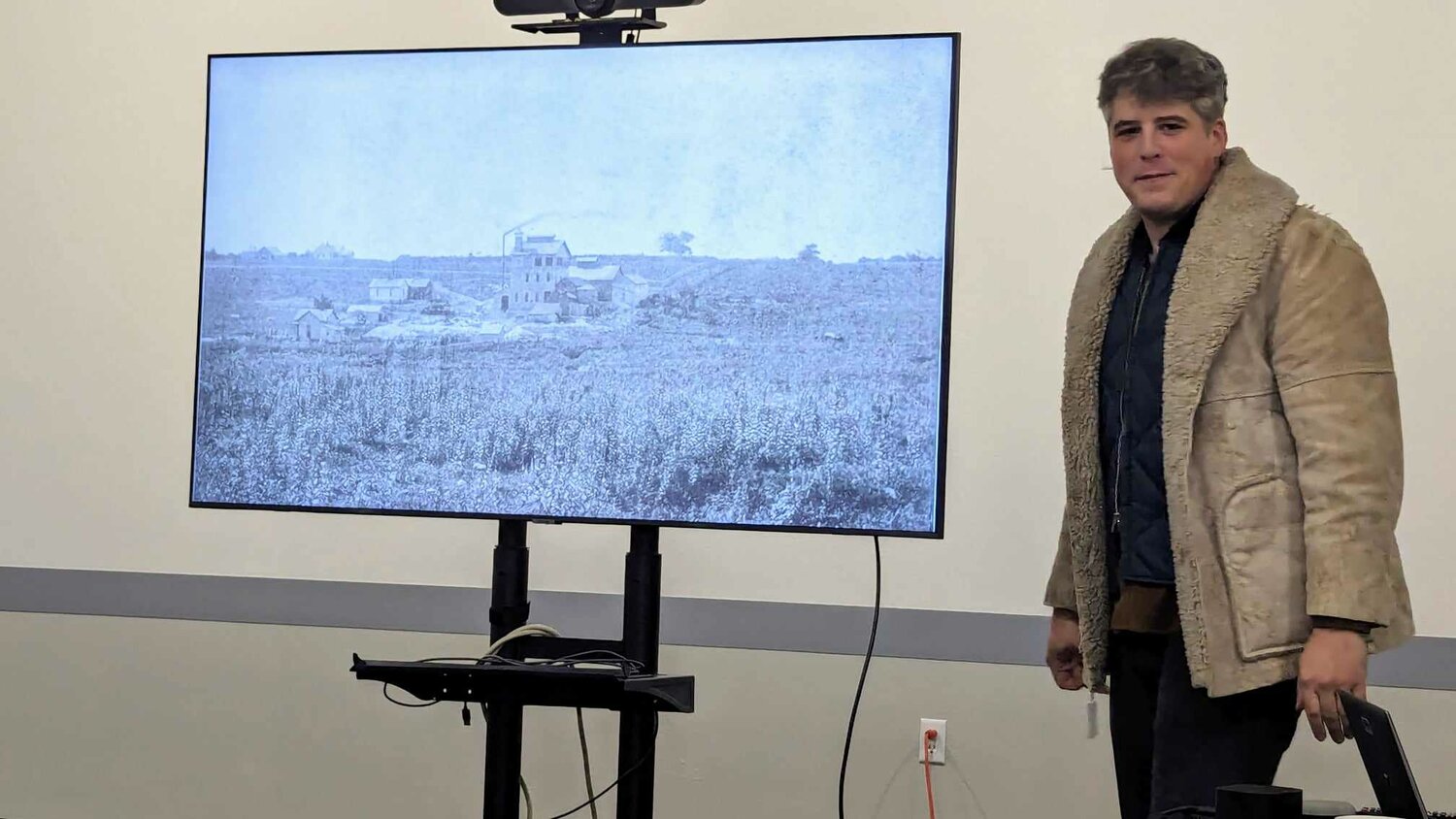 Caleb Sanders, a conservation coordinator with the Springfield-Greene County Park Board, shows an 1873 photo of Springfield as a treeless prairie centered by the old Fulbright house – today the site of Springfield Brewing Co. in the 300 block of Market Street. 